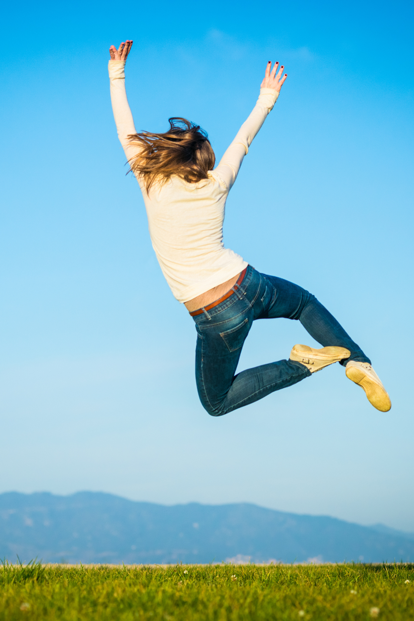 An image of a woman jumping joyfully in the air against a clear blue sky, symbolizing achievement and celebration. This visual represents the concept of a success story.