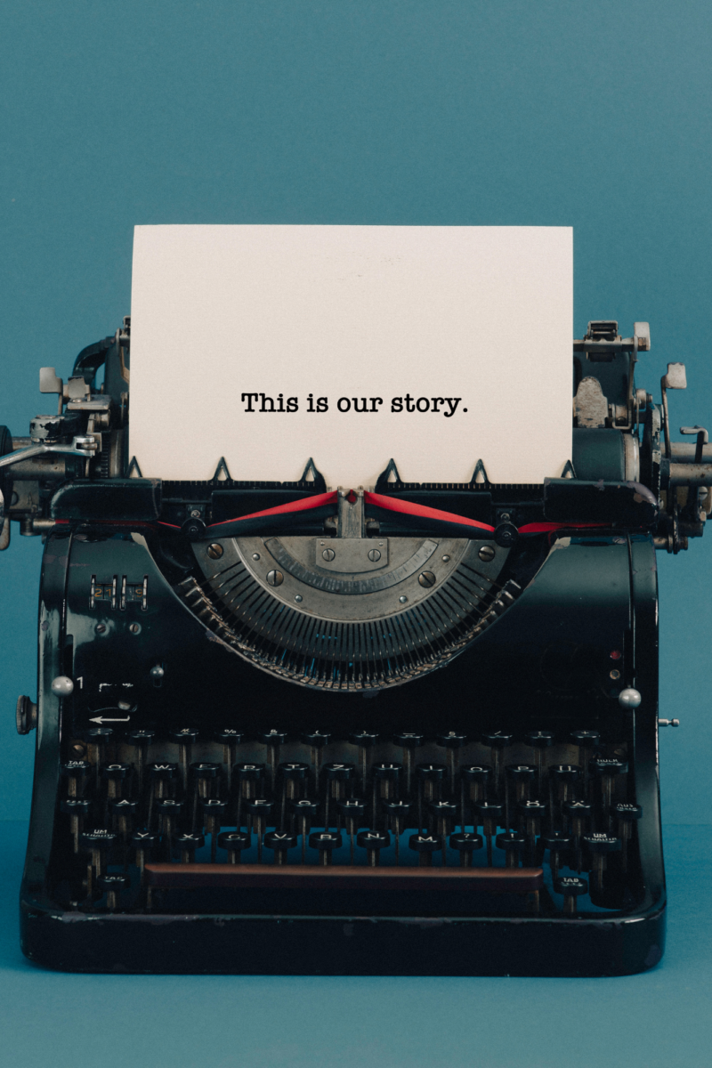 A vintage black typewriter with a piece of paper that reads "This is our story," set against a blue background, symbolizing storytelling, creativity, and crafting narratives.